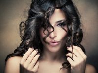 sensual brunette woman with shiny curly silky hair studio shot